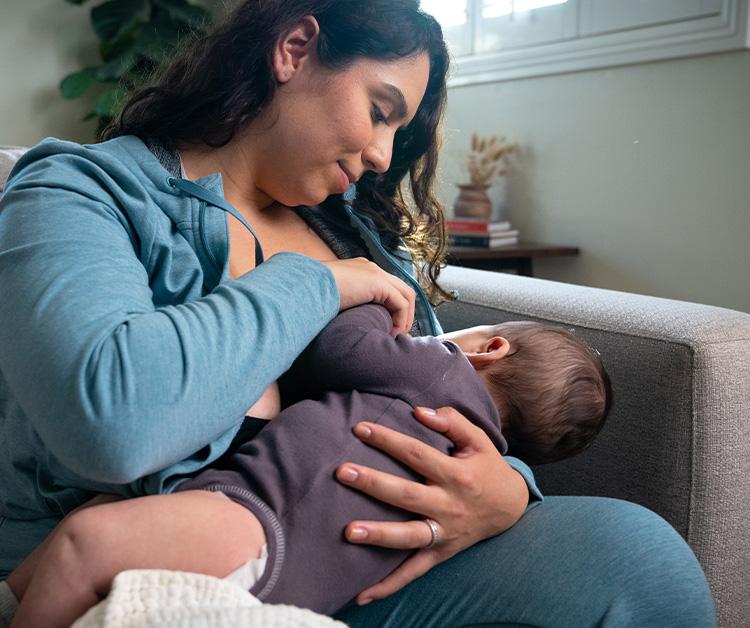 Smiling mother breastfeeding baby in a position to prevent acid reflux.