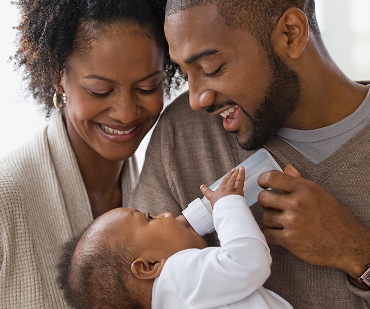 Mamá y papá felices alimentando a su bebé con un biberón