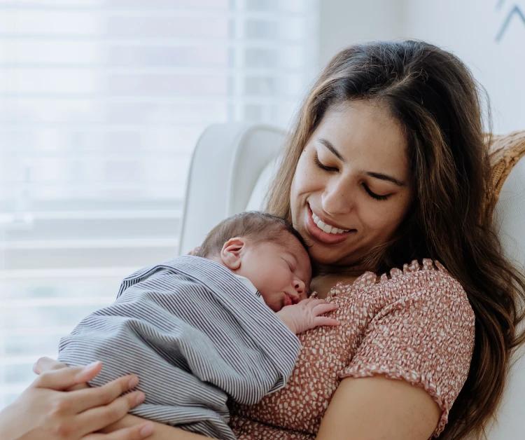 Mom sitting in a chair and holding a sleeping baby