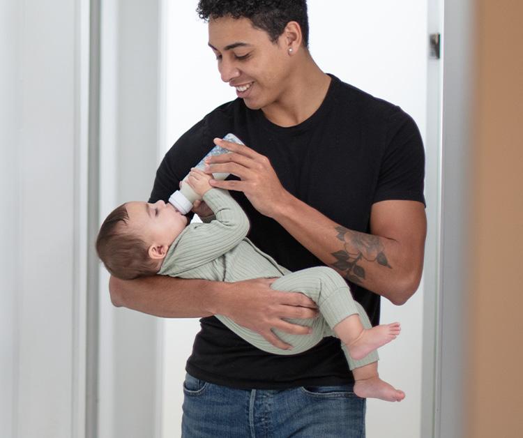 Dad cradling baby in arms and bottle feeding