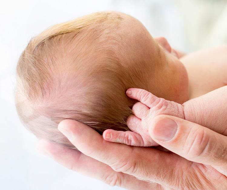 Parent Holding Newborn In Hands