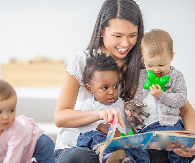 Daycare professional paying with group of toddlers