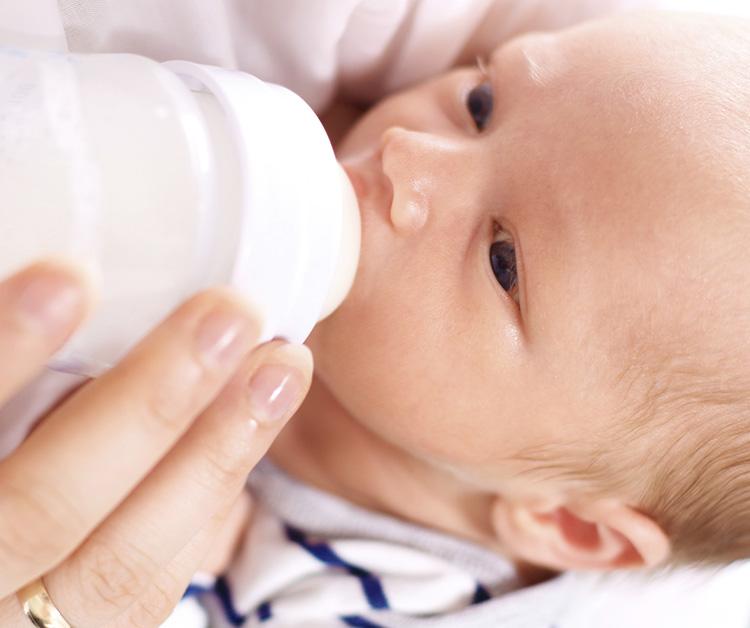 Baby being held while drinking a bottle