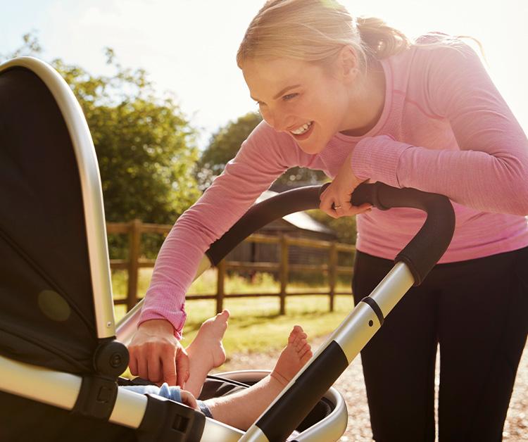 Mom smiling at baby in a stroller during their walk