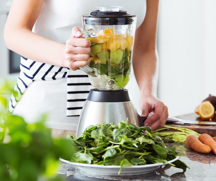 Woman putting vegetables in a blender