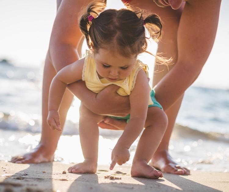 Toddler girl playing in the sand with parent