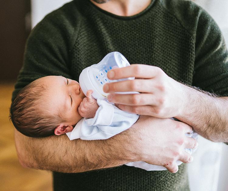 Dad bottle feeding his newborn