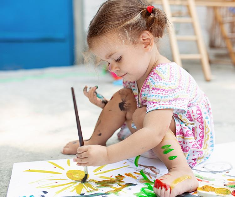 Little girl painting with a paint brush