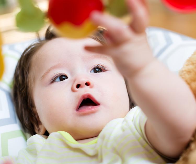 baby playing with toy while lying on a play mat