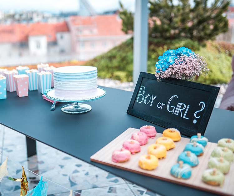 Sign reading "Boy or Girl?" on a table with desserts