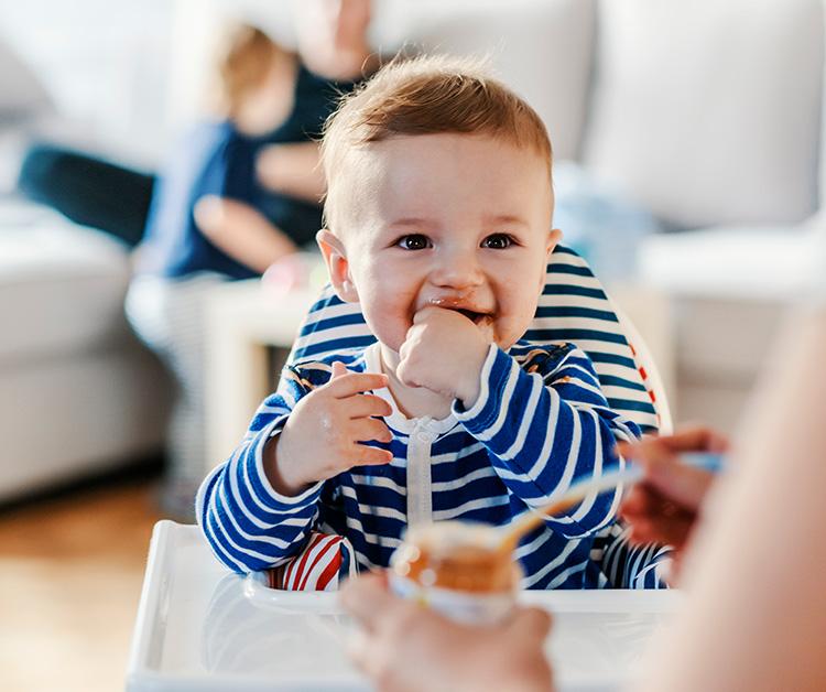 Baby sitting in a high chair eating baby food