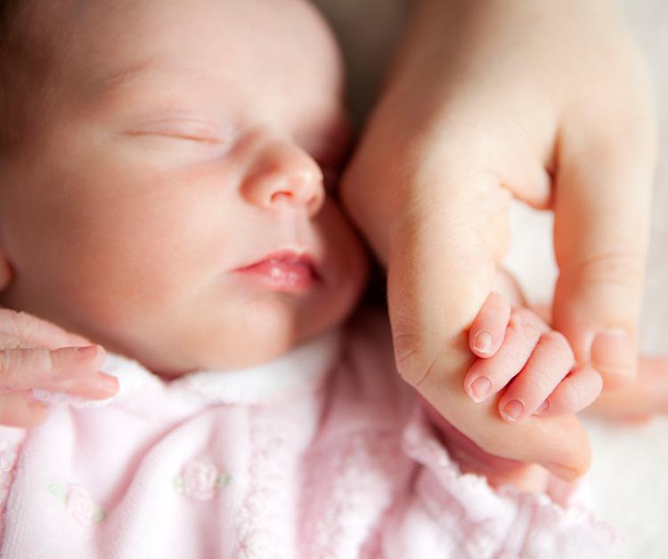 Baby holding moms hand while sleeping
