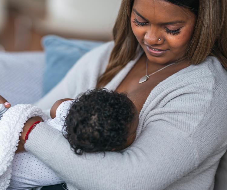 Woman in a gray sweater breastfeeding her child
